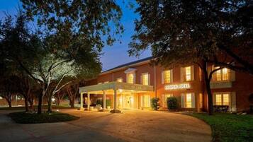 A hotel with a covered entrance, a sign reading "COOPER HOTEL," and a well-lit facade.