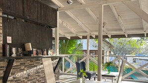 Un interior moderno con techo de madera, pared de piedra, mesa de comedor con sillas y vista al exterior.