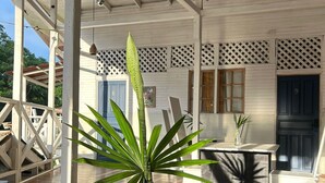 Una terraza de madera con una mesa, libros, una planta alta y una puerta marcada con el número 9.
