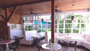 Un restaurante con vigas de madera en el techo, mesas blancas y sillas negras.