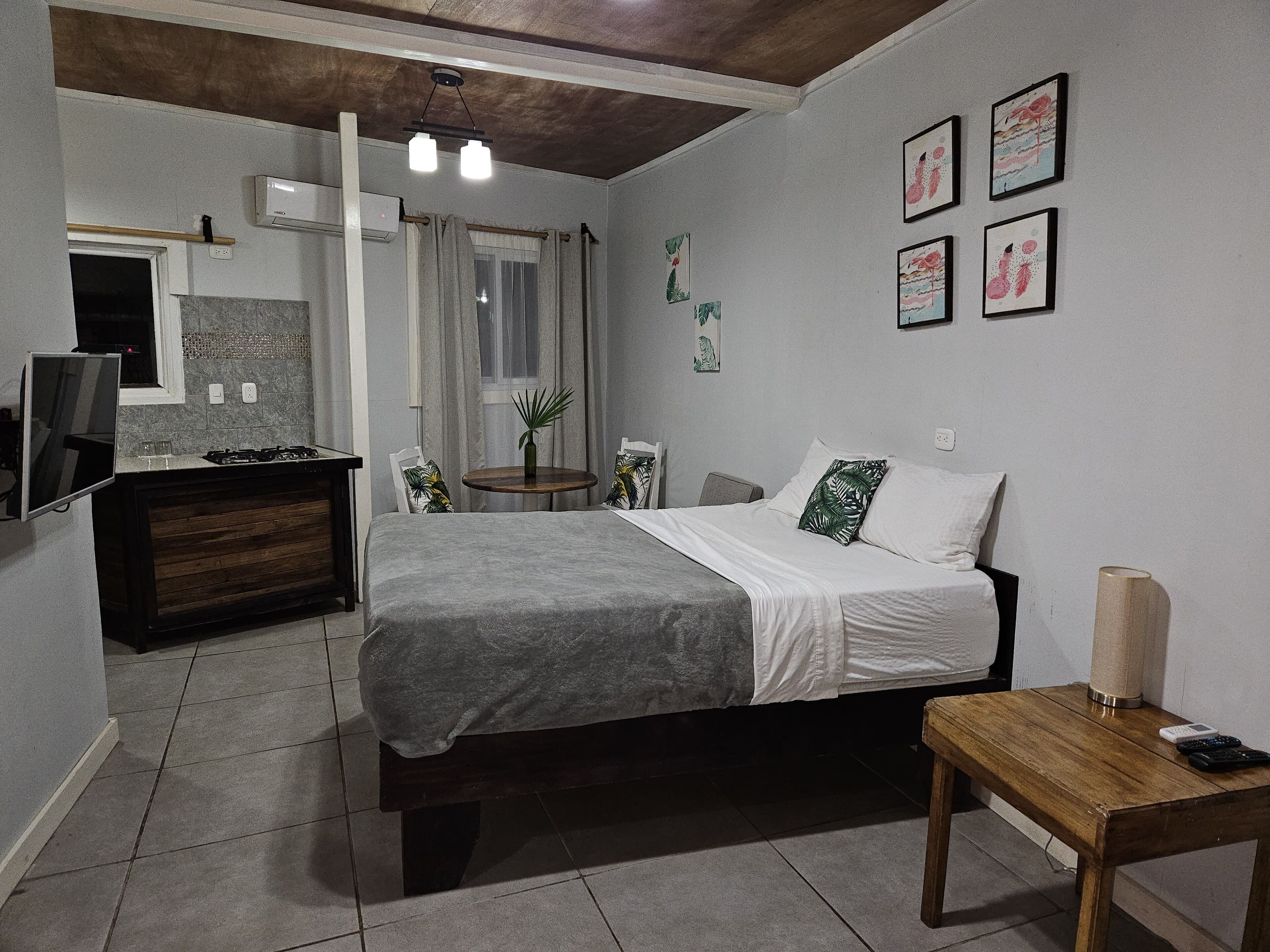 A bedroom with a bed, bedside table, and a small round table with a plant.
