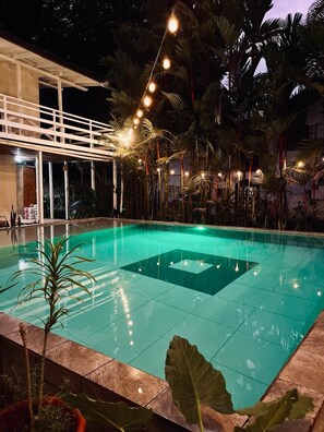 A swimming pool with a geometric tile pattern, surrounded by palm trees and a wooden deck. - Lizard King Hotel & Suites (Cahuita)