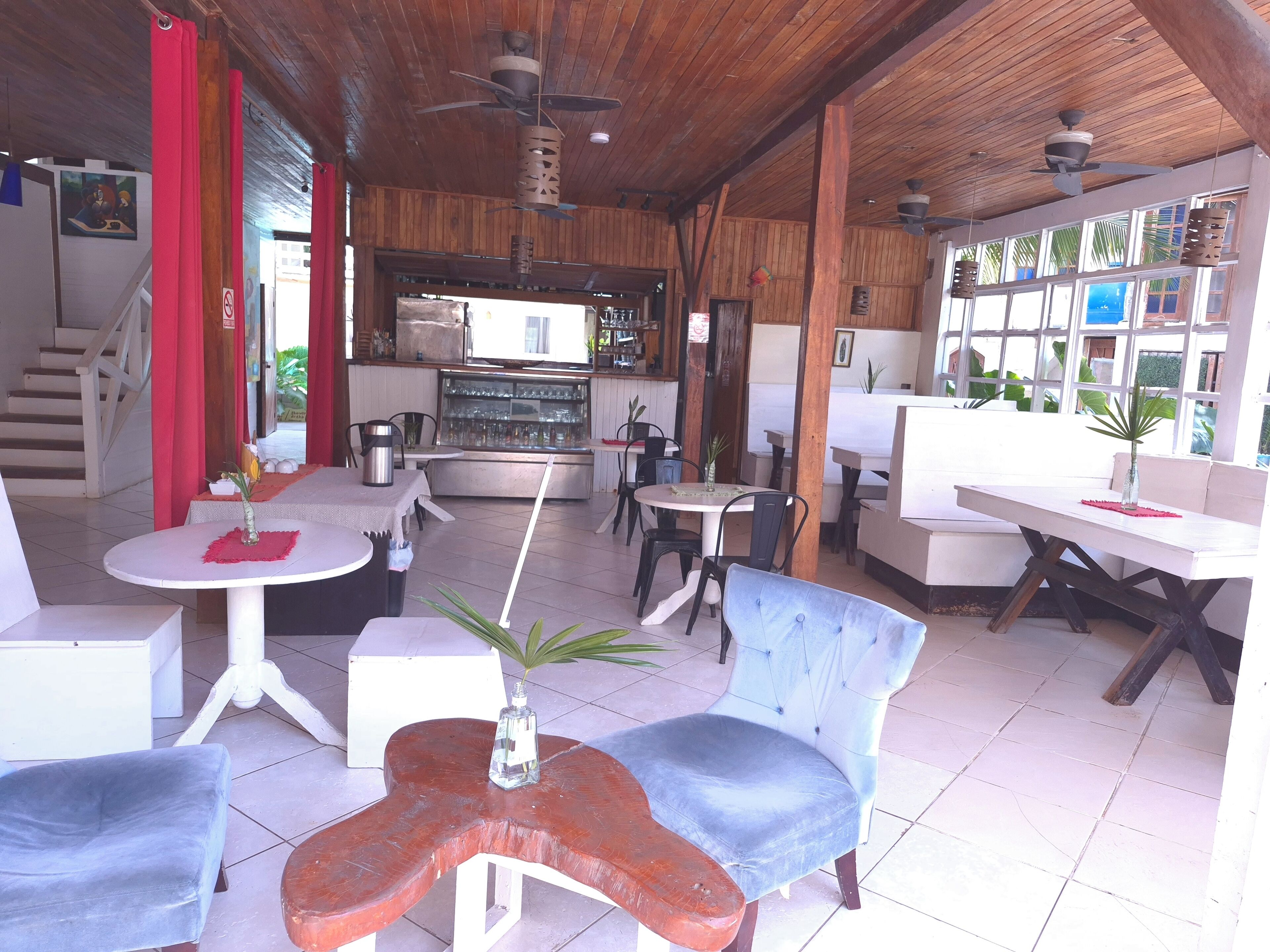 Un restaurante con techo de madera, varias mesas, sillas y una zona de bar.