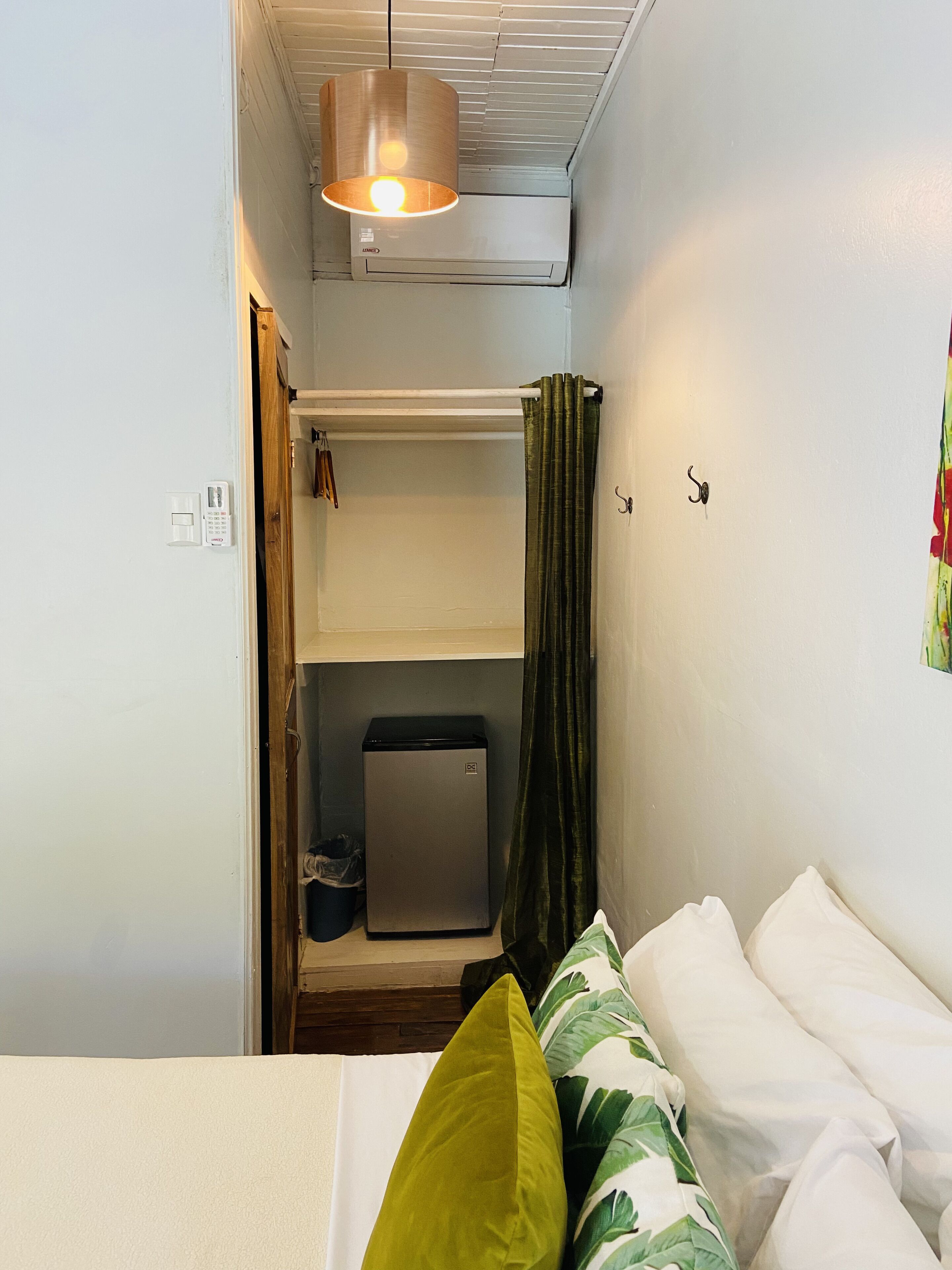 Habitació senzilla amb llit, un petit escalfador, nevera petita i cortina.