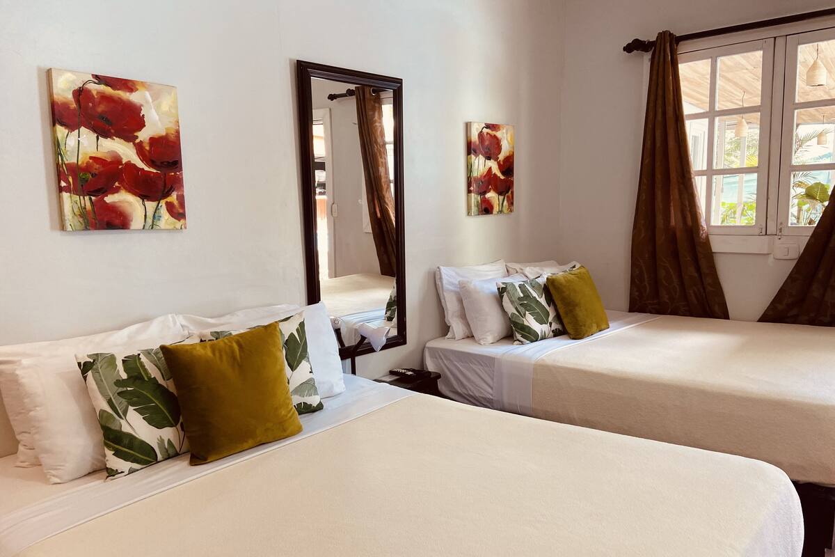 A hotel room with two beds, a large mirror, and artwork on the walls.