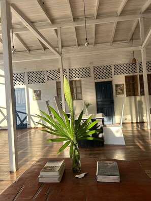 A room with a wooden ceiling, a large plant, and books on a table. - Lizard King Hotel & Suites (Cahuita)