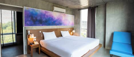 Quarto de hotel moderno com uma cama grande, abajures, uma cadeira azul e uma grande pintura abstrata na parede.