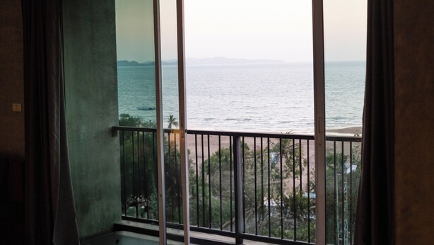 A balcony with a view of the sea and a distant shoreline.