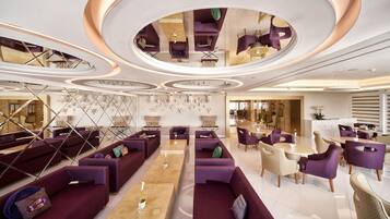 A modern hotel lobby with purple seating, wooden tables, and a unique ceiling design.