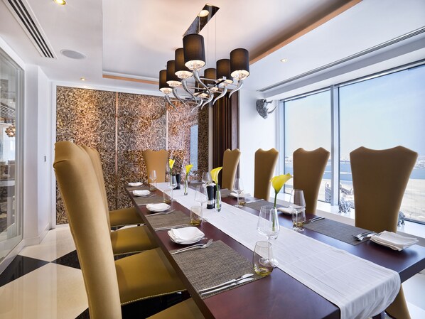 Un comedor con una mesa larga, sillas altas y una lámpara moderna.