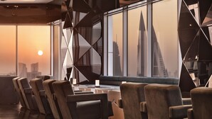Eine moderne Lounge mit Ledersesseln, einem spiegelnden Boden und einem großen Fenster mit Blick auf die Stadt.