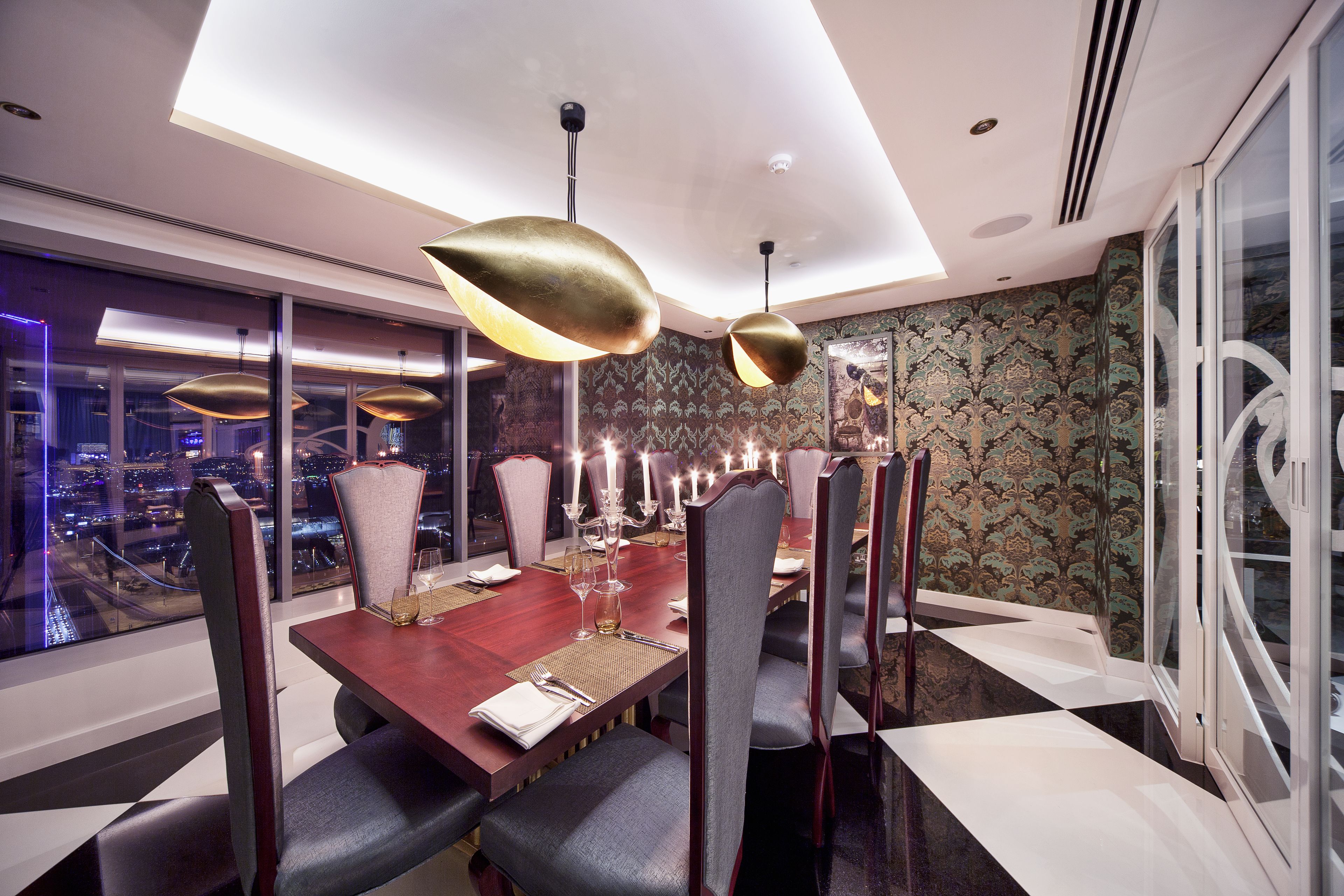 Un comedor moderno con una mesa grande, sillas elegantes e iluminación colgante.