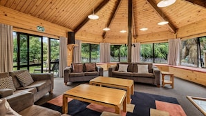 A spacious room with wooden ceilings, large windows, and multiple seating areas including sofas and a coffee table. - Altamont Lodge (Wanaka)