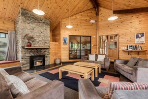Un interior de cabaña acogedor, con chimenea de piedra, paredes de madera y una zona de estar confortable.