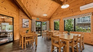 A wooden interior with a dining area, wooden tables and chairs, and large windows. - Altamont Lodge (Wanaka)