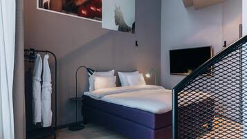 A modern bedroom with a bed, a TV, and a coat rack.