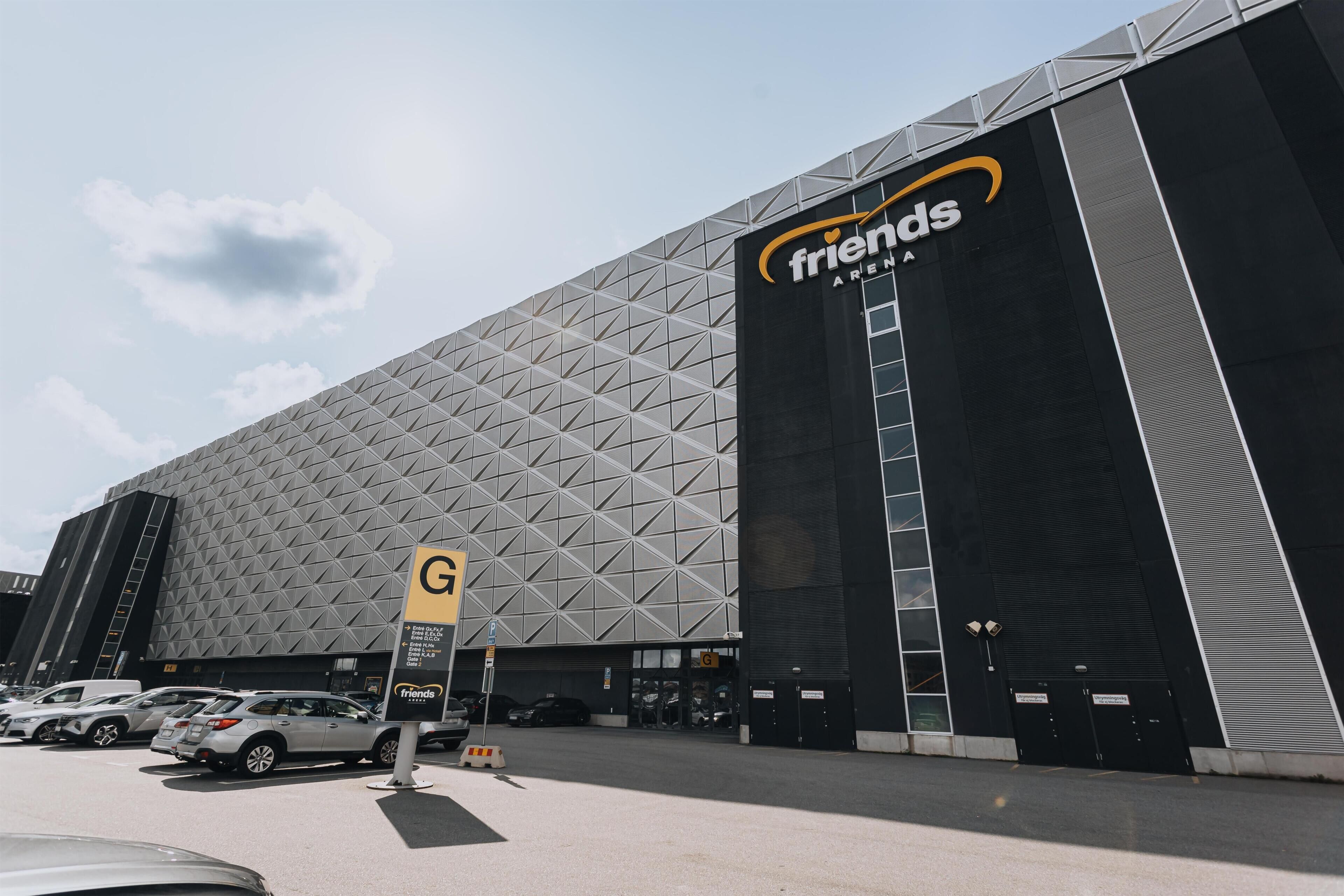 Un grand bâtiment à la façade géométrique, sur lequel on peut lire l’inscription « Friends Arena ».