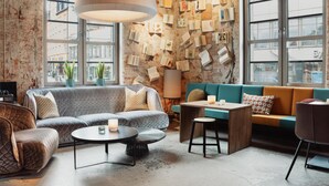 Un salon moderne avec un mur en briques, de grandes fenêtres, un canapé, une table basse et un luminaire suspendu.