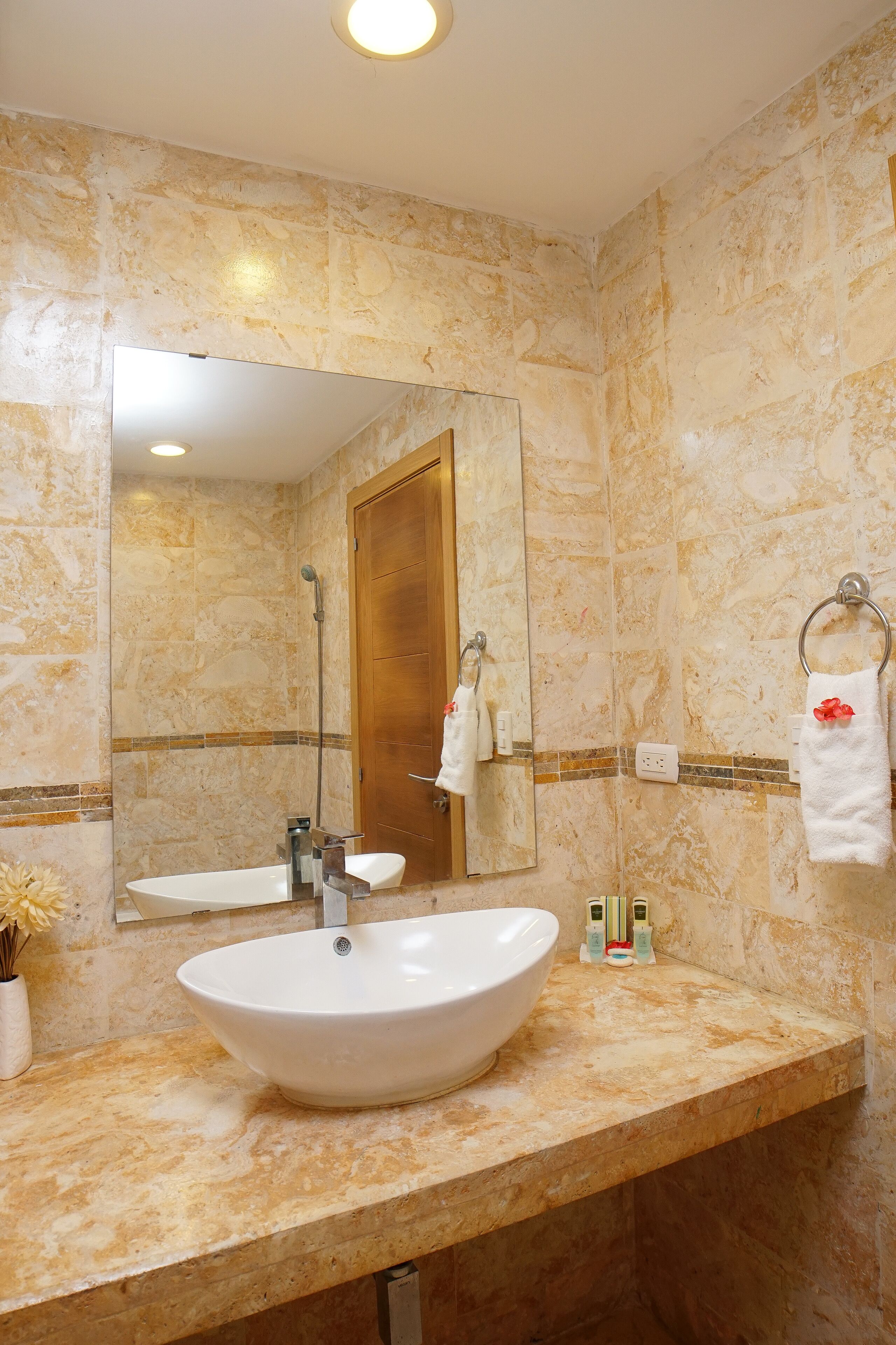 A bathroom with a large white sink, a mirror, and a wooden door.