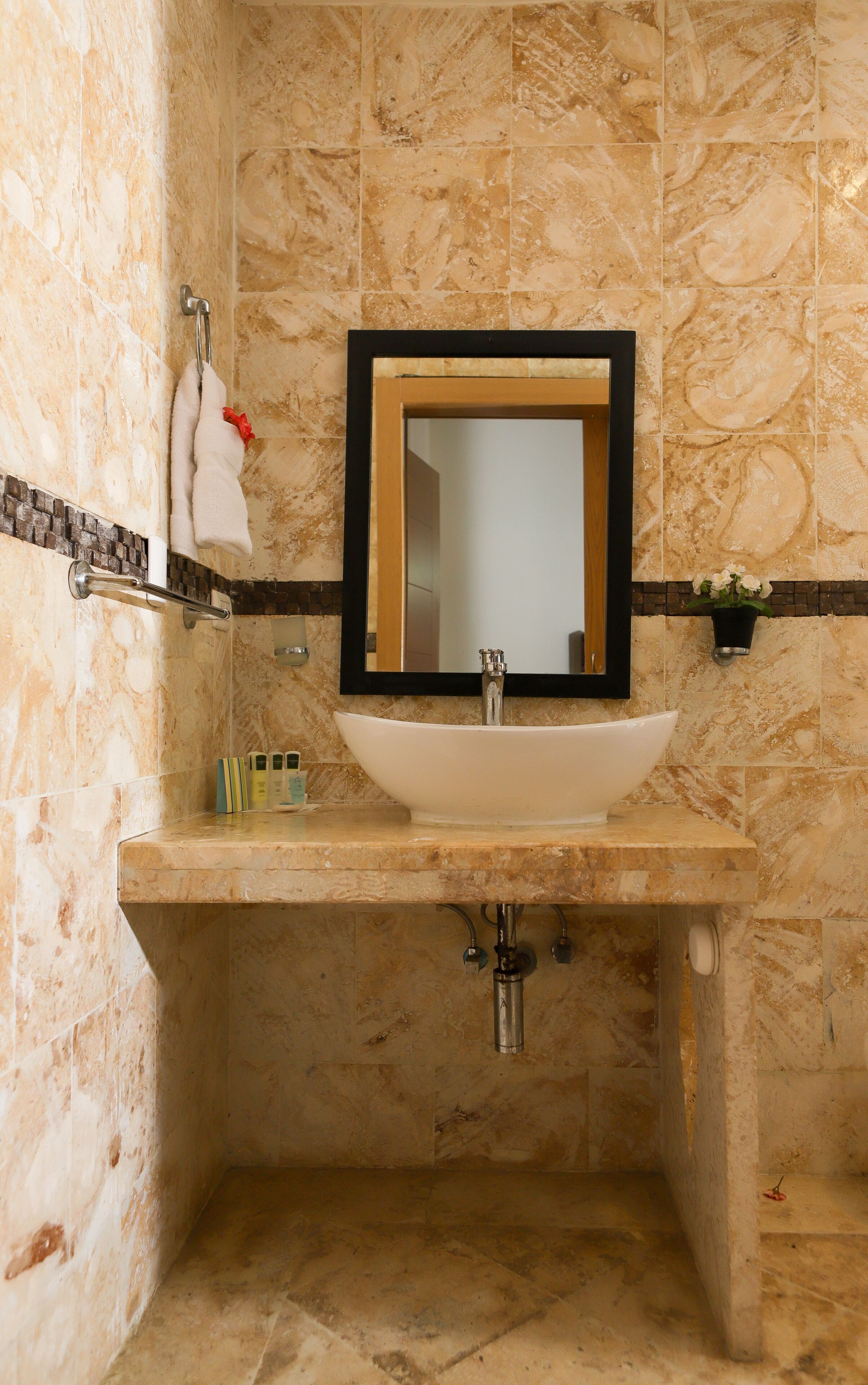 A bathroom with a marble sink, a mirror, and a towel rack.