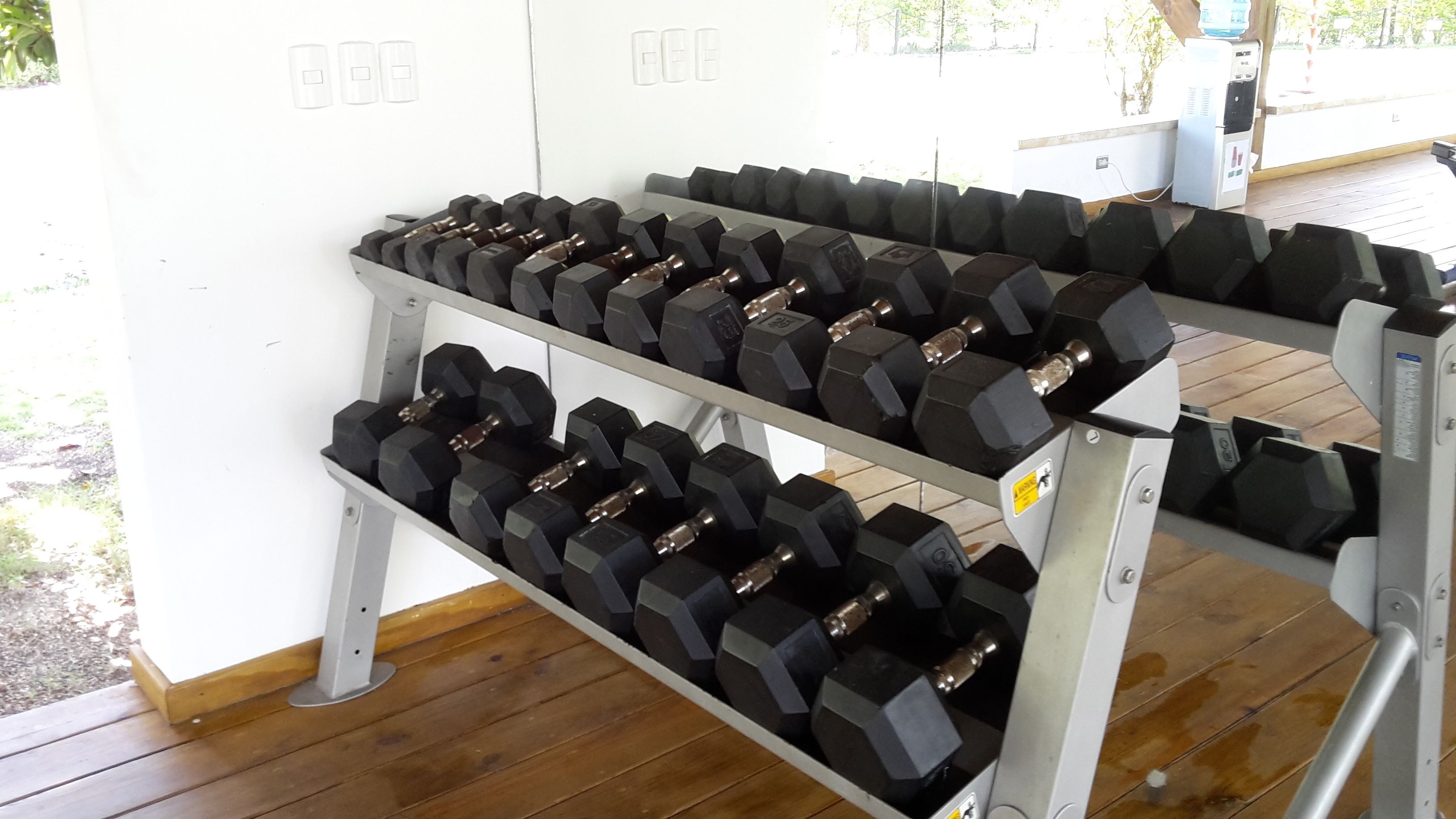 A gym with two rows of black dumbbells on metal racks.