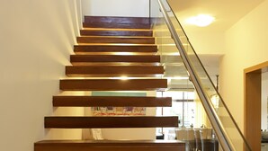 Un escalier en bois avec des rampes en verre menant à un espace repas.