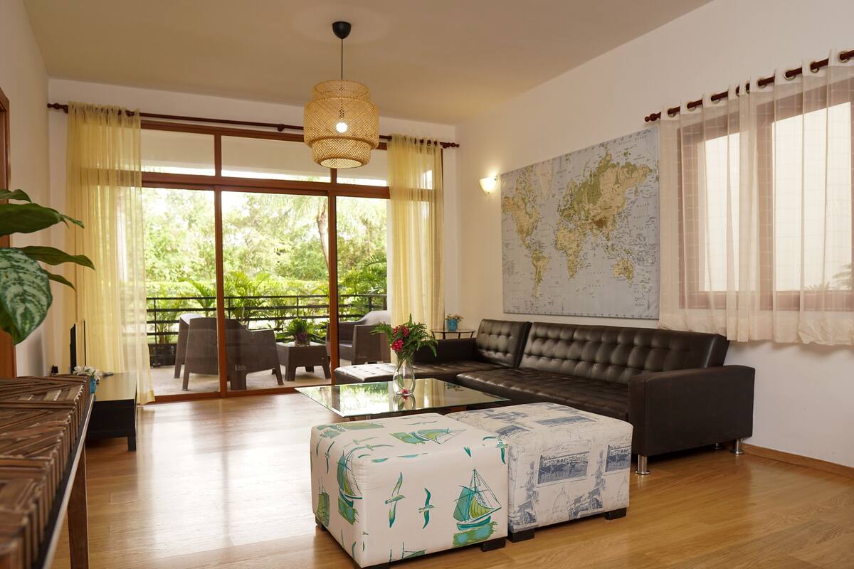 A spacious living room with a large sofa, a coffee table, and a map on the wall.