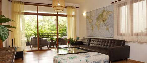 A spacious living room with a large sofa, a coffee table, and a map on the wall.