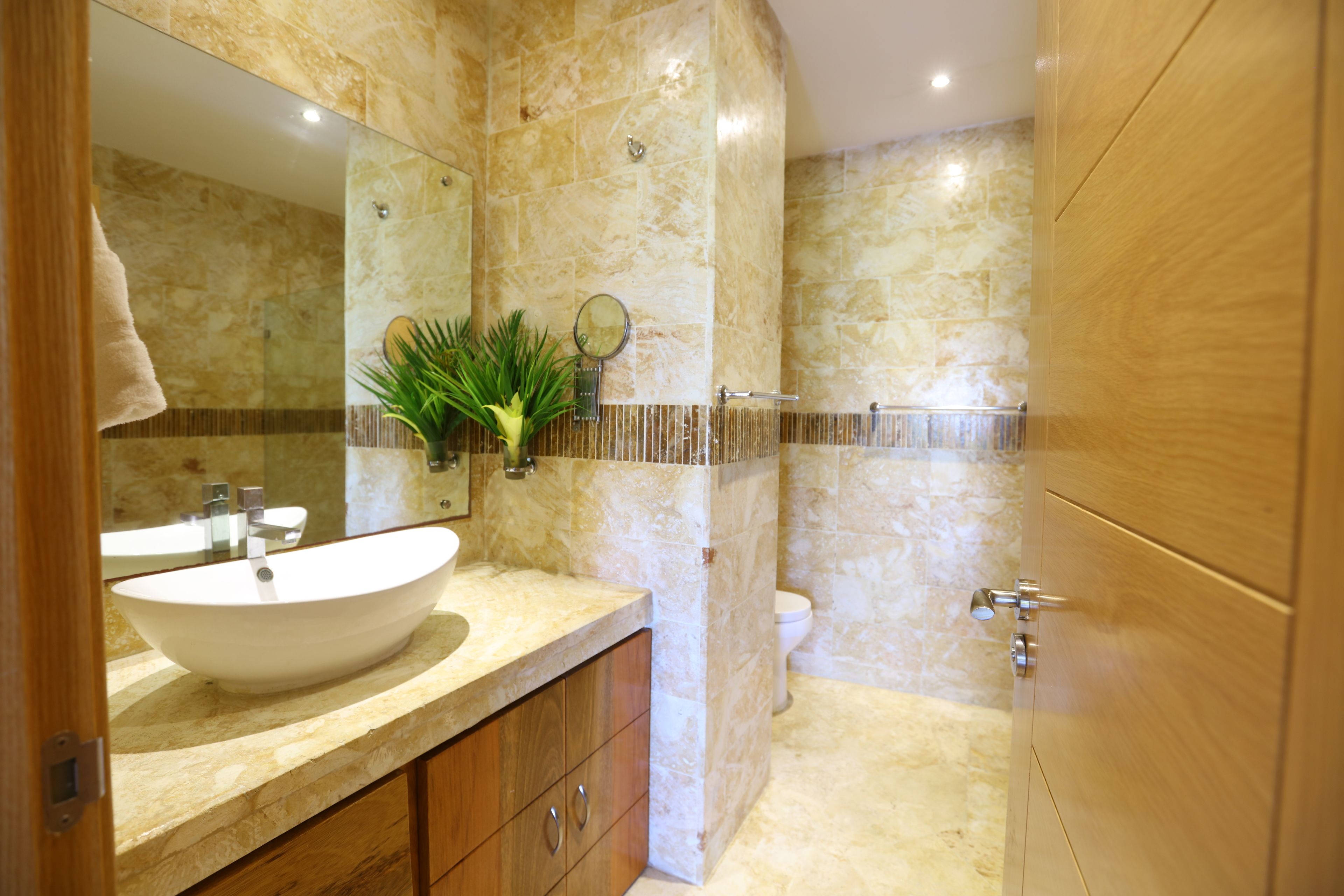 A bathroom with a large mirror, a sink, a toilet, and a shower area.