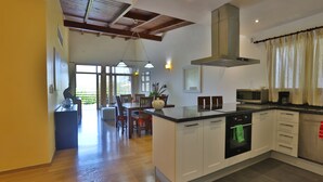Une cuisine spacieuse dotée d’un plancher en bois, d’un îlot central et d’un coin repas avec des chaises et une table.