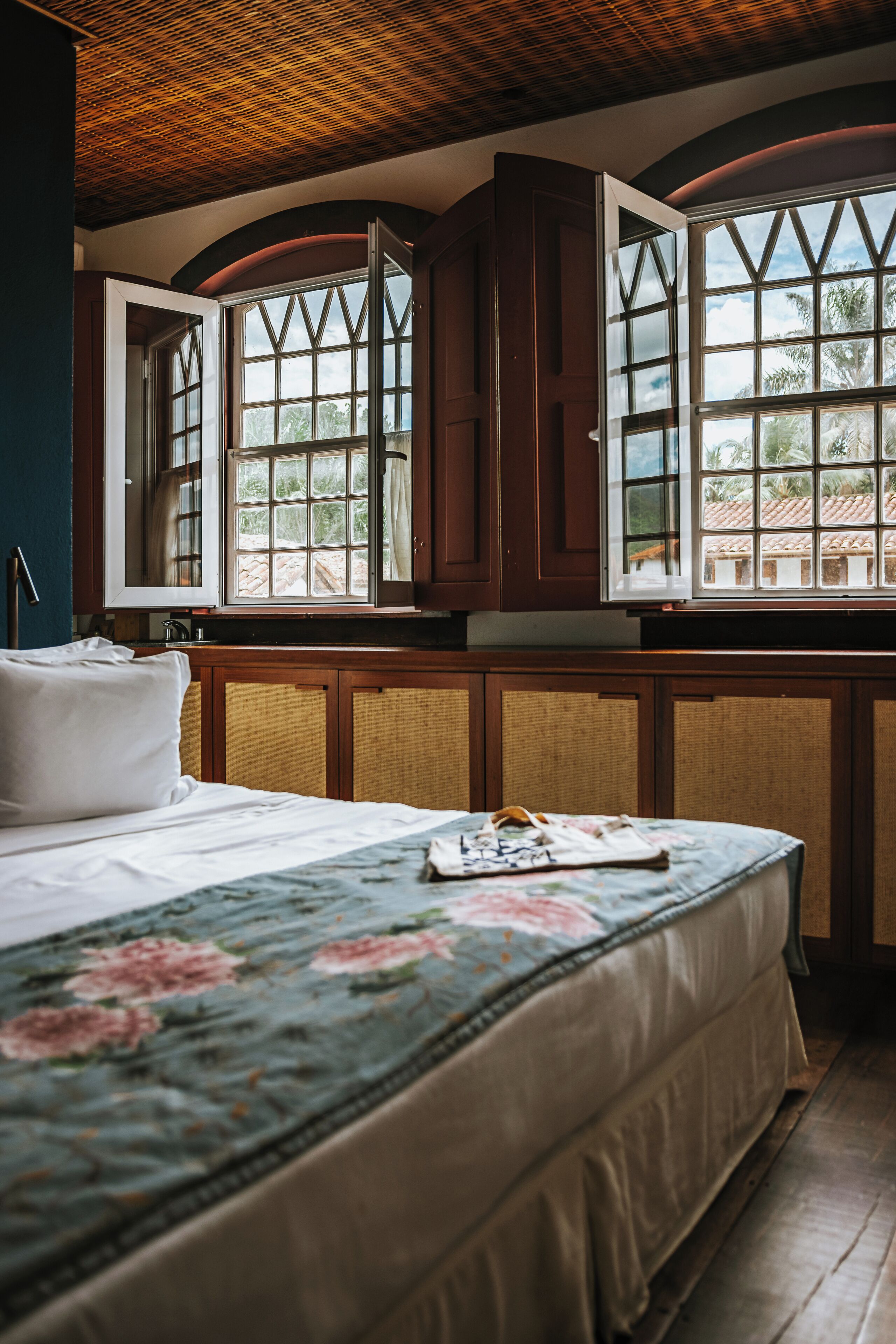 A bedroom with a bed, a window with curtains, and a view of the outside.