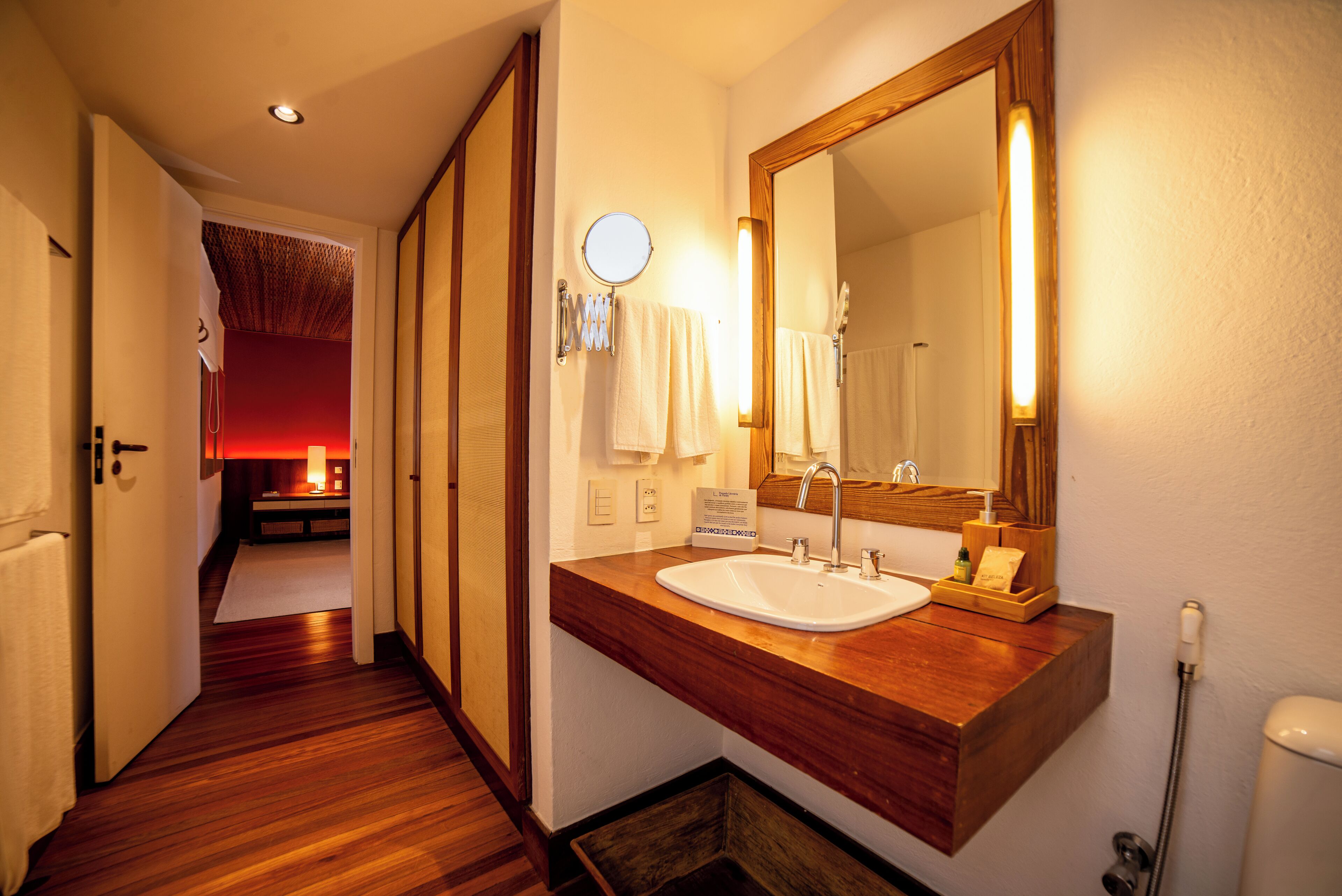 A hotel bathroom with a wooden vanity, a large mirror, and a sink.