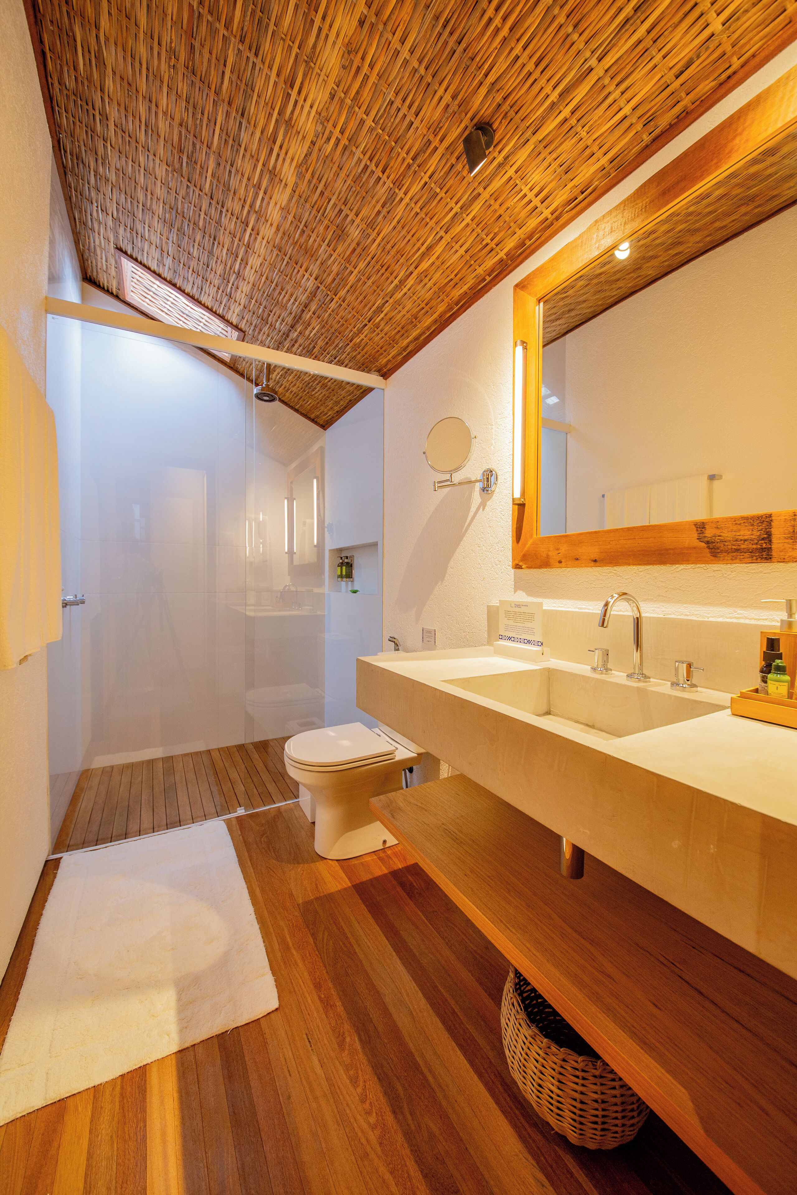 A bathroom with a wooden ceiling, a large mirror, a sink, and a toilet.