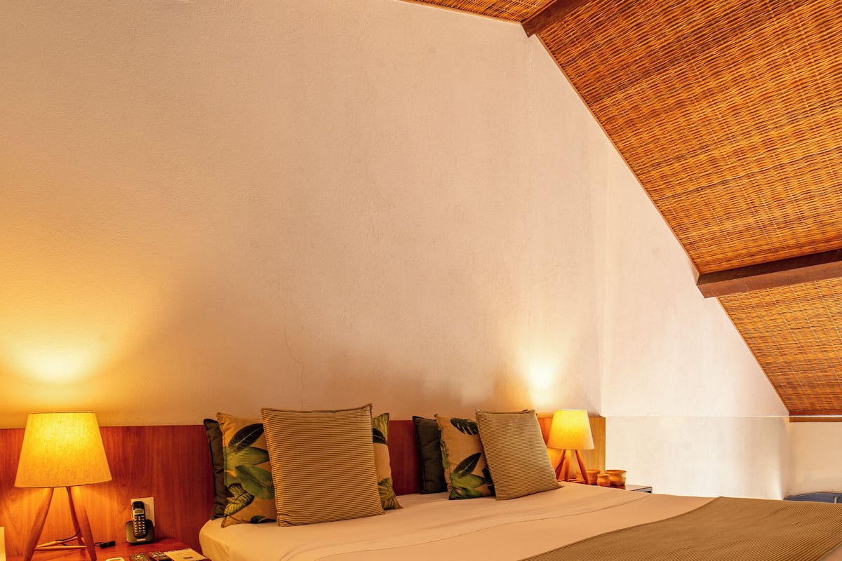 A cozy bedroom with a large bed, wooden headboard, and a sloped ceiling.