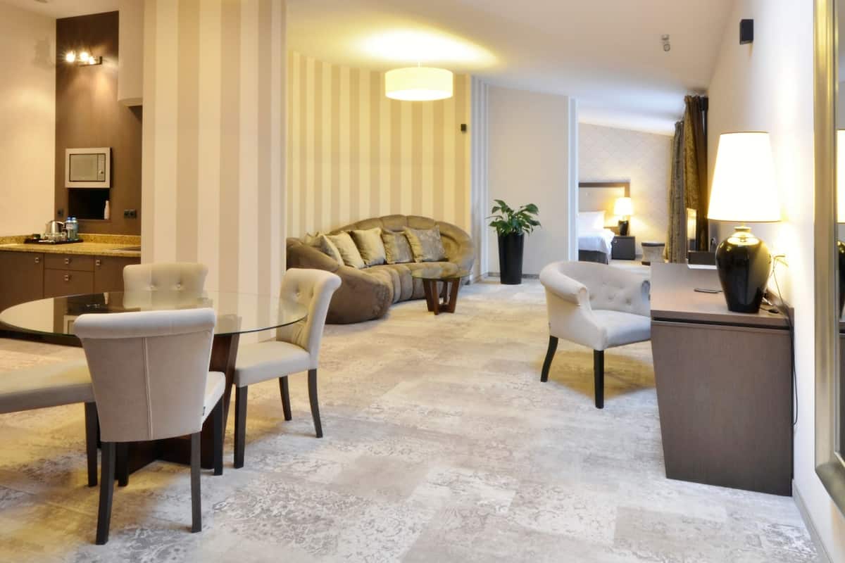 Ein modernes Hotelzimmer mit Essbereich, einer Couch, einem kleinen Tisch und einem großen Spiegel.