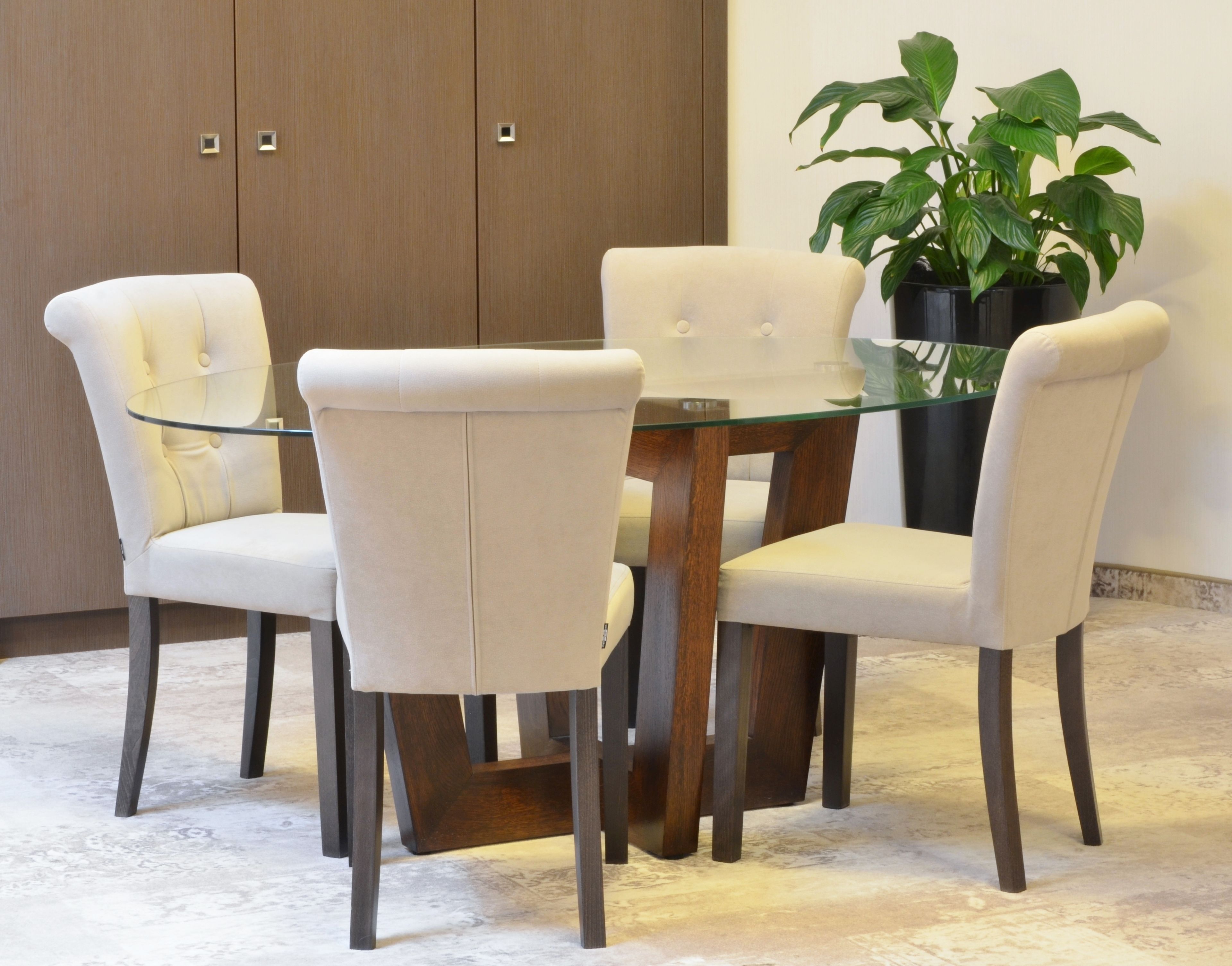 Un coin repas avec une table à plateau en verre, entourée de quatre chaises rembourrées.