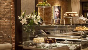 Un restaurante con pared de ladrillo, vitrina con postres y una silla de cuero marrón.