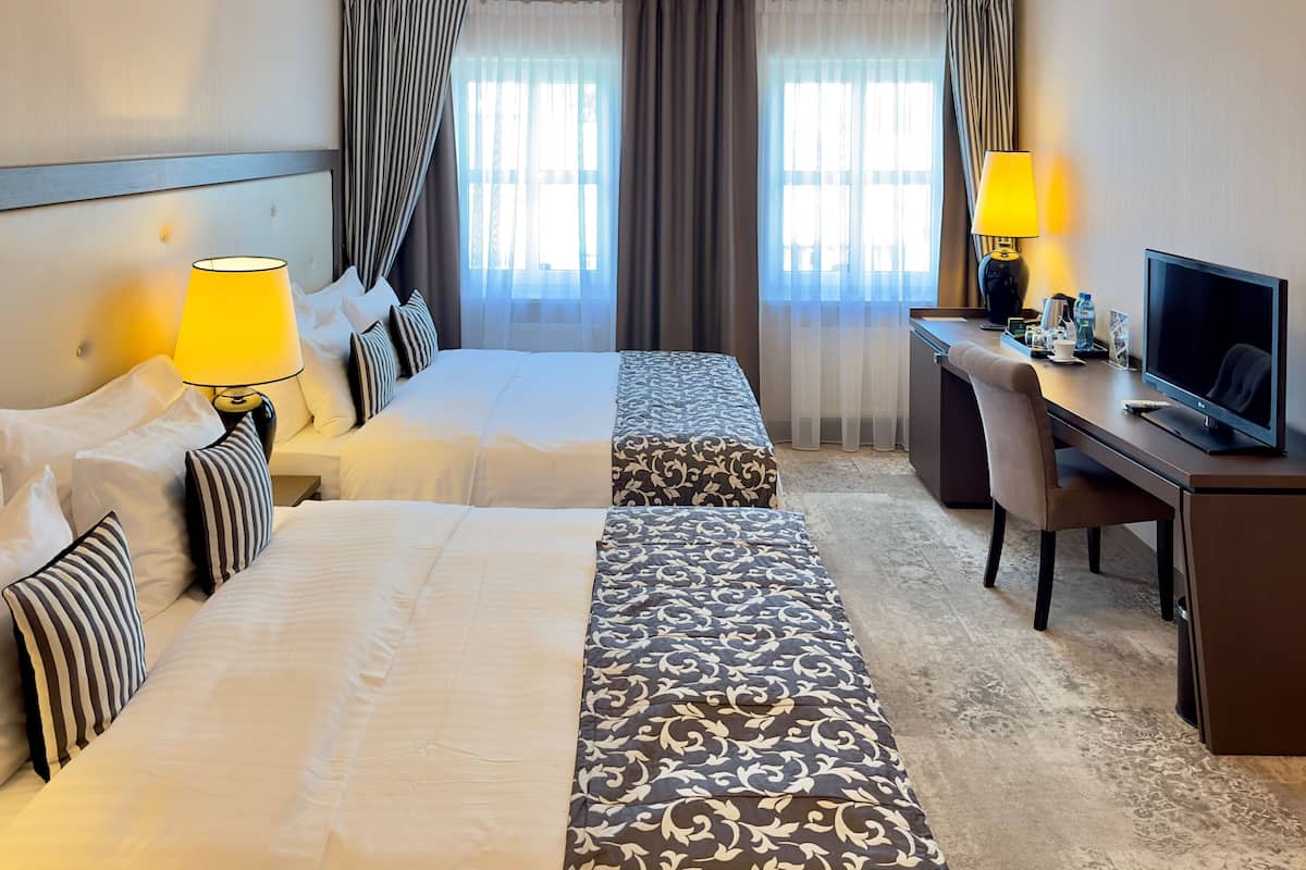 Ein Hotelzimmer mit zwei Betten, einem Schreibtisch, einem Fernseher und einem Sessel.