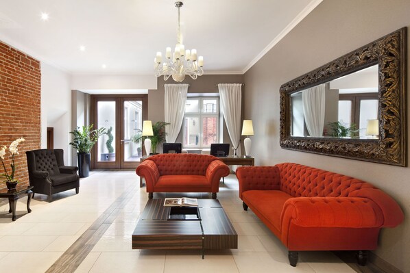 A spacious living area with a modern sofa, a coffee table, and a large mirror. - Metropolitan Boutique Hotel (Kraków)