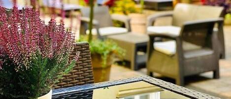 Un café en plein air, avec une table dressée pour le petit-déjeuner, comprenant des croissants, du café et des viennoiseries.