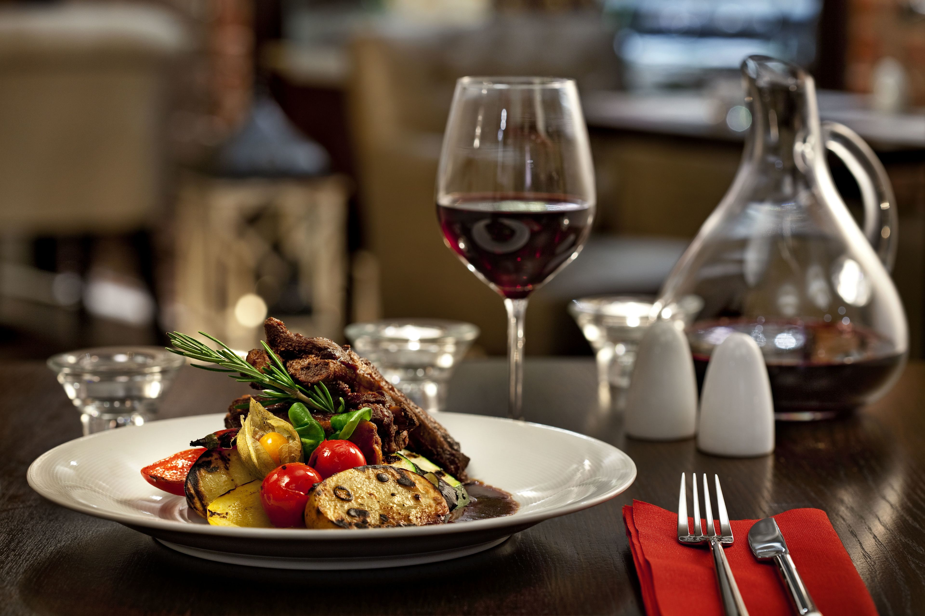 A dining table with a plate of food, a wine glass, and a pitcher.