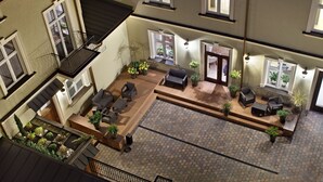 Un patio amplio con cubierta de madera, mobiliario exterior y plantas en macetas.