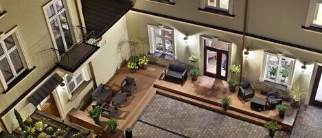 A spacious courtyard with a wooden deck, outdoor seating, and potted plants.
