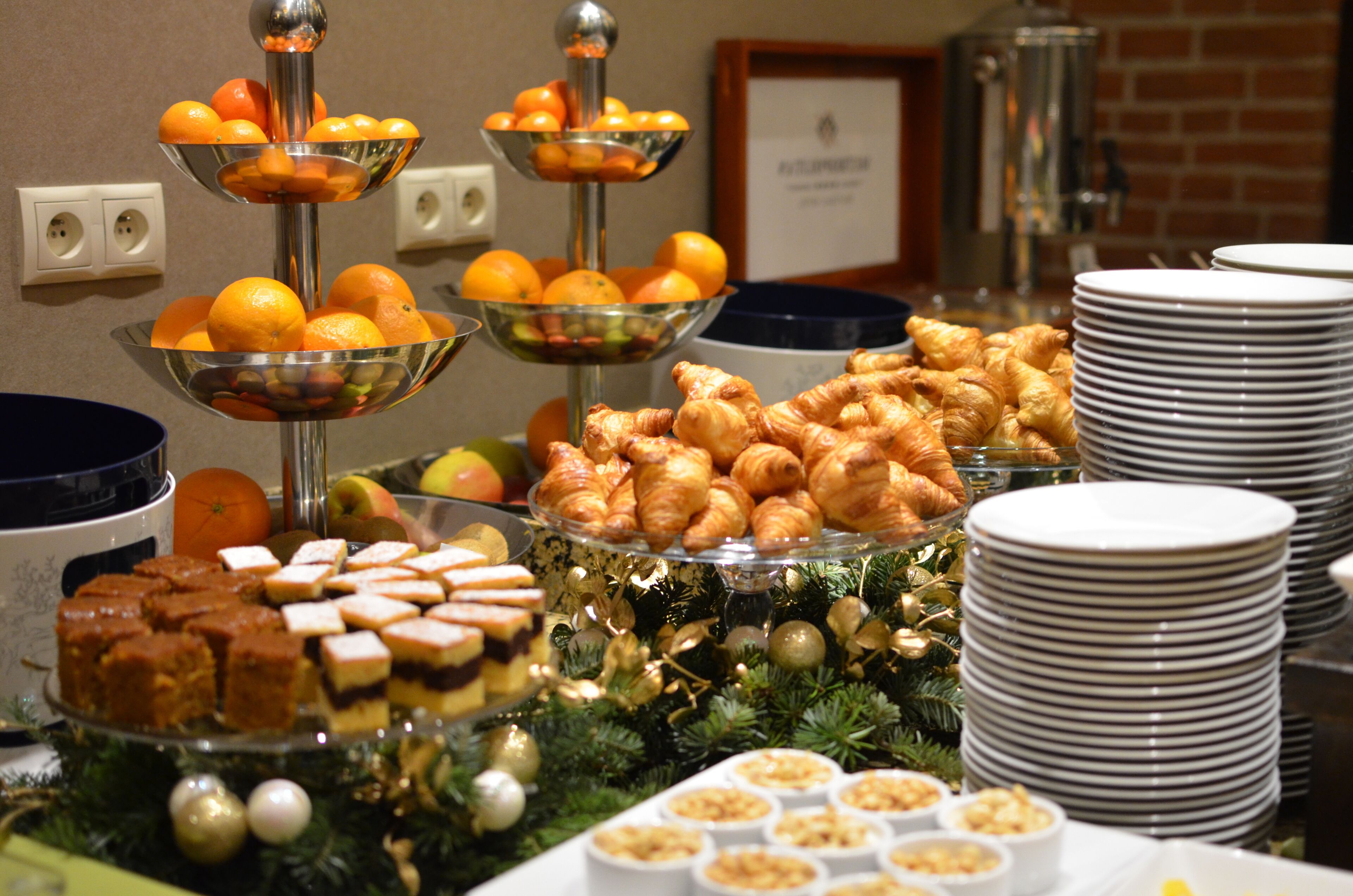 A buffet with various food items including oranges, pastries, and desserts.