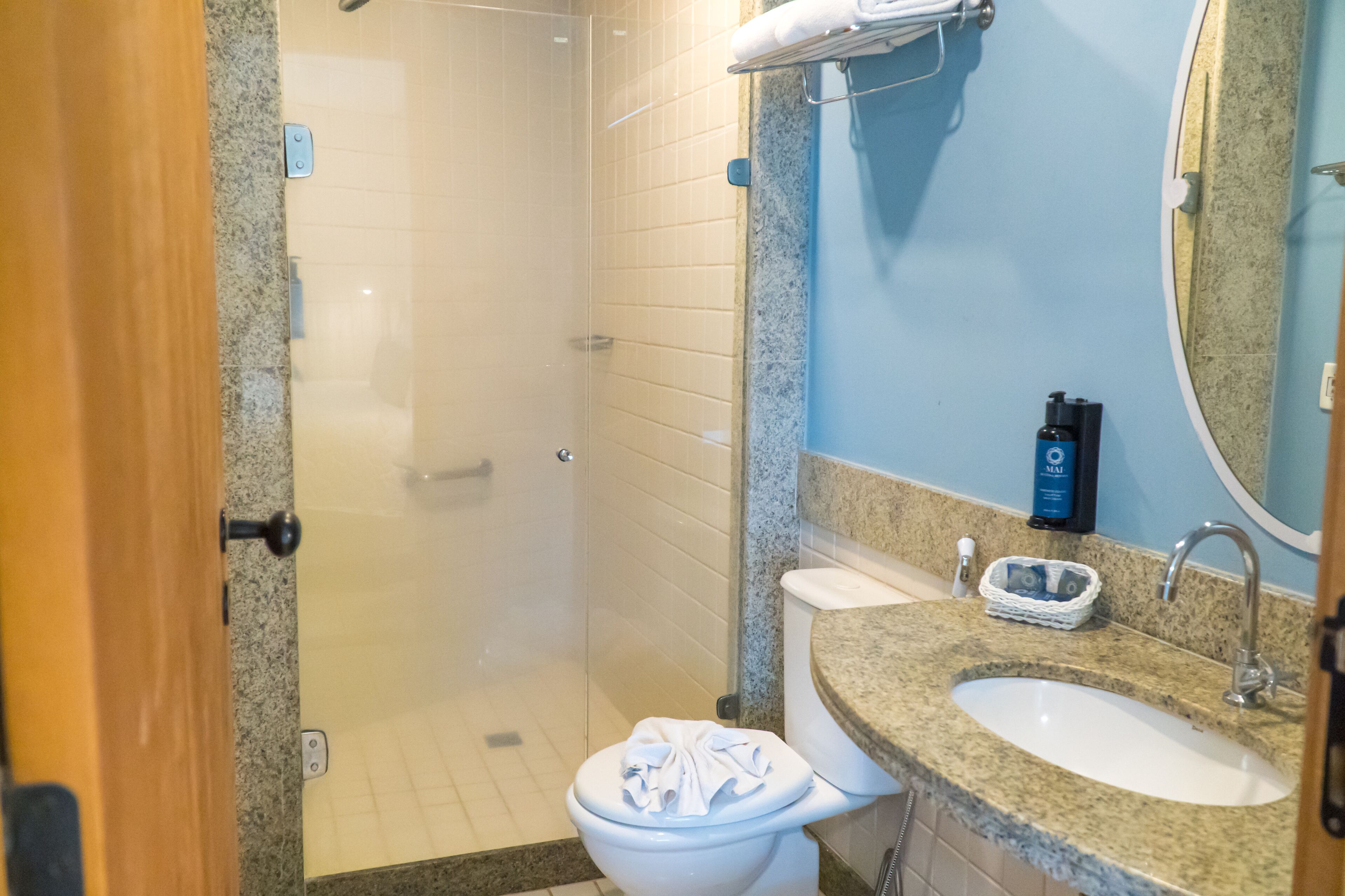 A bathroom with a shower, toilet, sink, and a mirror.