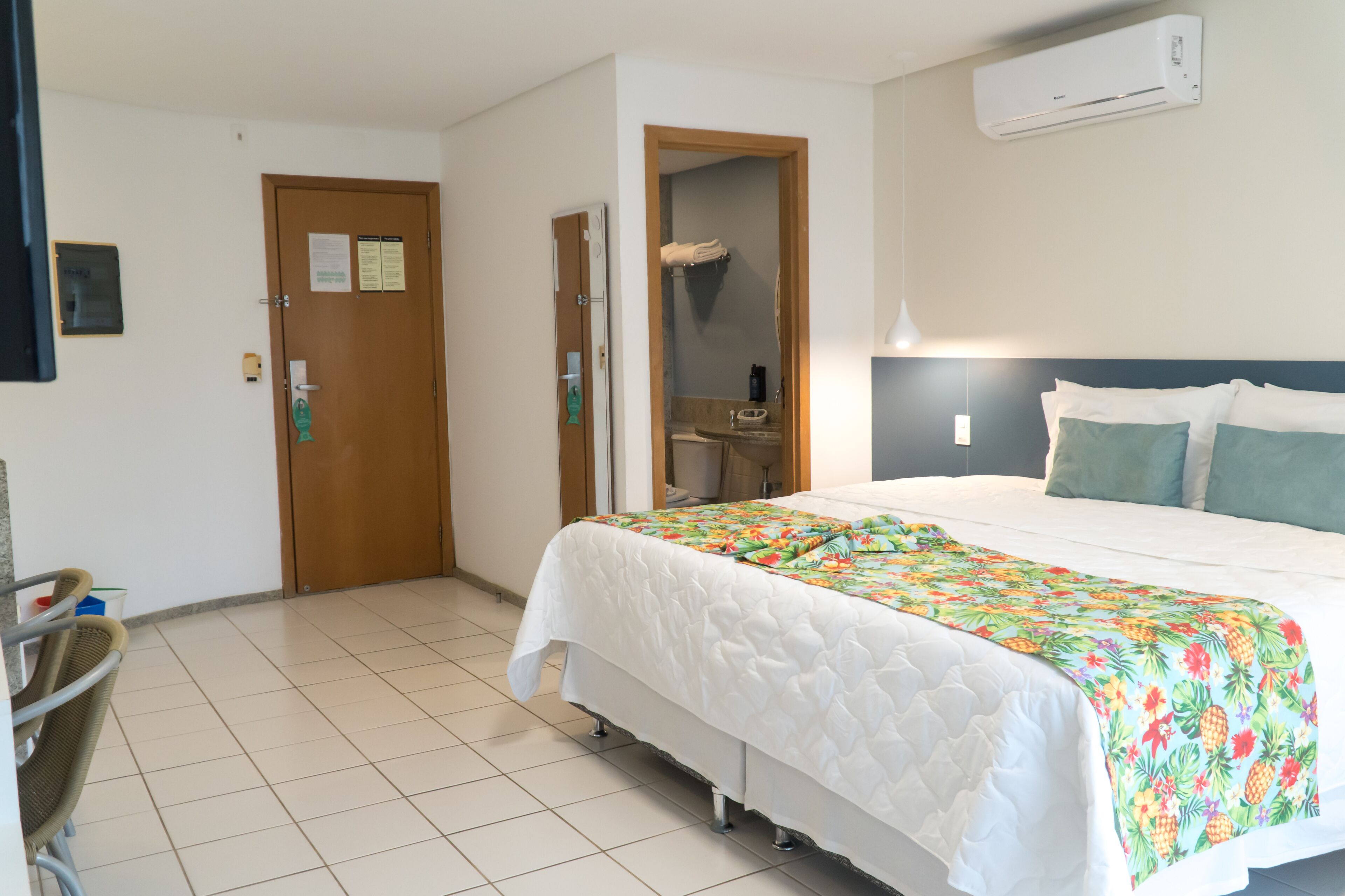 Una habitación de hotel con una cama, un escritorio y un baño visible a través de una puerta abierta.