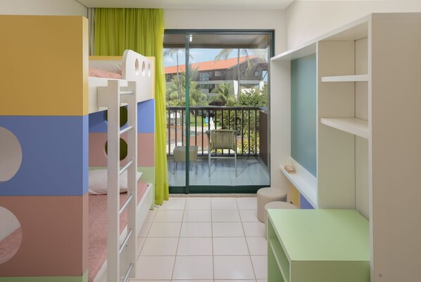 A child's room with bunk beds, a balcony with a view of palm trees, and a small table.
