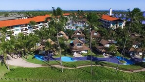 Et resort med flere bygninger, et poolområde og palmer.
