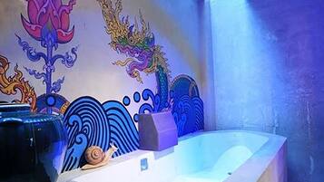 Un baño con bañera, una pared decorativa con un mural de dragón y una luz azul.