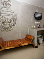 A room with a wooden bench, a television mounted on the wall, and a decorative wall mural.